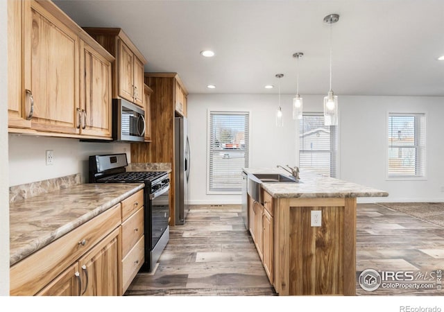 kitchen with an island with sink, light wood-type flooring, appliances with stainless steel finishes, and recessed lighting