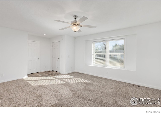 carpeted empty room featuring visible vents, ceiling fan, and baseboards