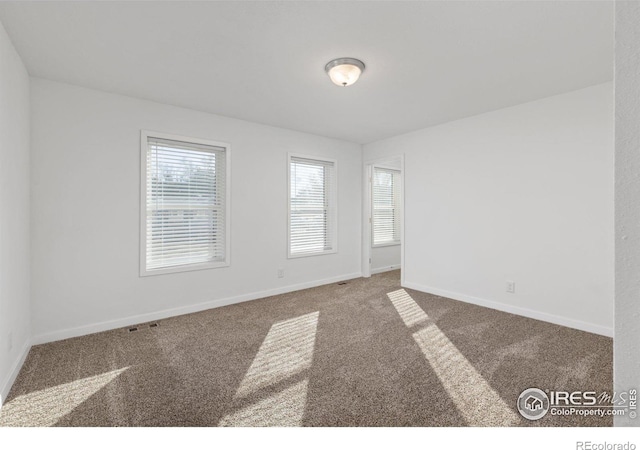 carpeted empty room with visible vents and baseboards