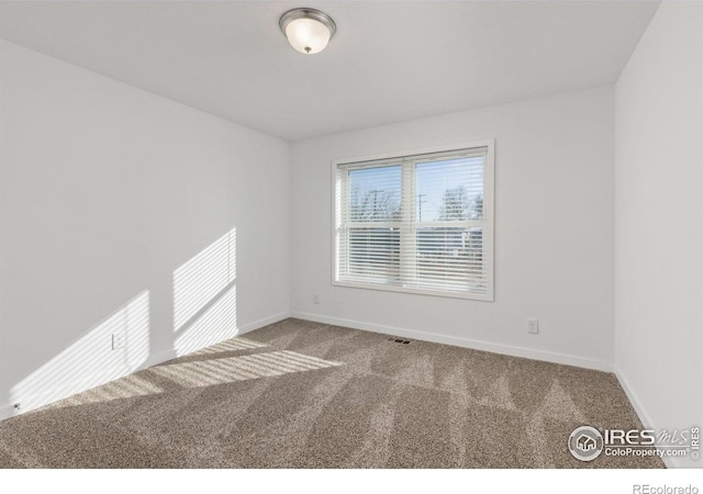 carpeted spare room with visible vents and baseboards