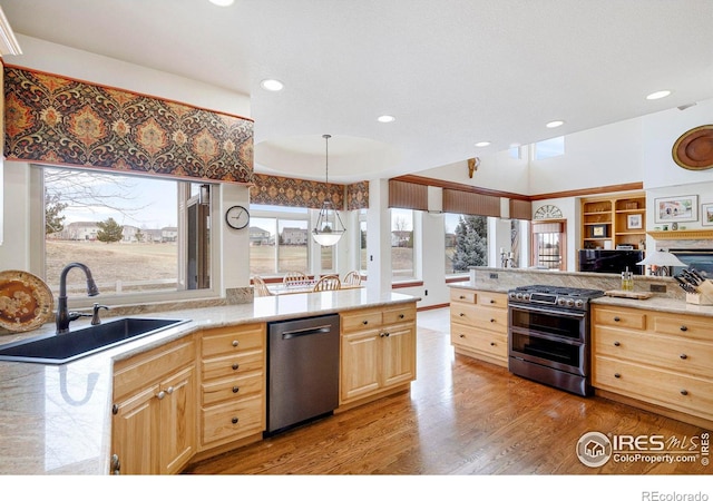 kitchen featuring appliances with stainless steel finishes, a peninsula, light countertops, light brown cabinets, and a sink