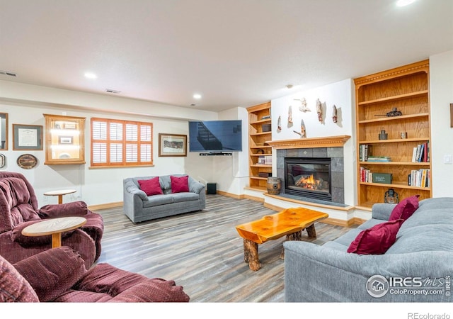 living area with visible vents, a fireplace, baseboards, and wood finished floors