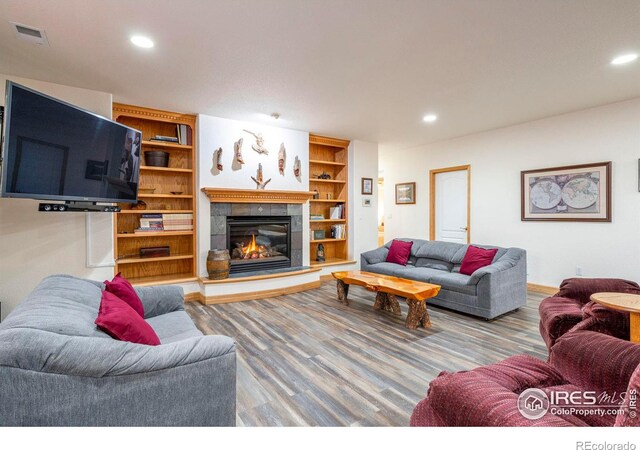 living area featuring a fireplace, wood finished floors, visible vents, and recessed lighting