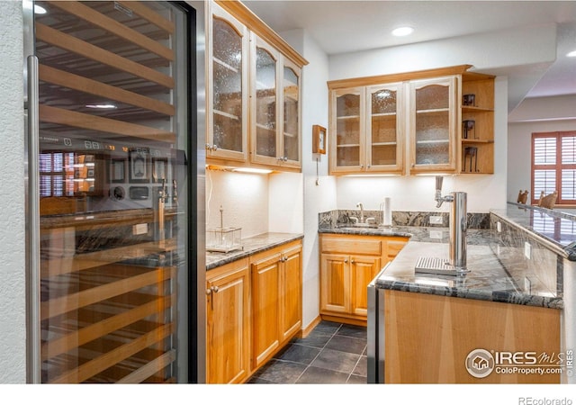 kitchen with dark tile patterned floors, dark stone countertops, glass insert cabinets, and recessed lighting