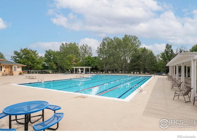 community pool featuring fence, a pergola, and a patio