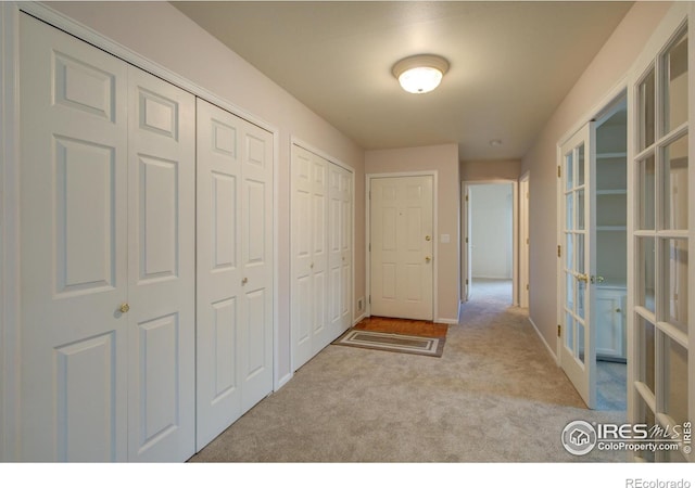 hall featuring baseboards, carpet flooring, and french doors