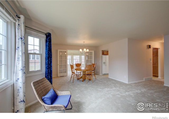 living area featuring baseboards, visible vents, a notable chandelier, and light colored carpet