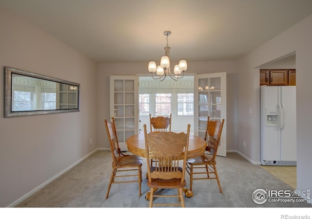 dining room featuring light carpet, an inviting chandelier, and baseboards