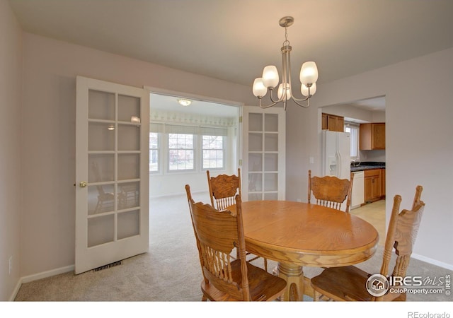 dining space featuring light carpet, baseboards, and an inviting chandelier