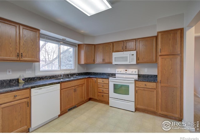 kitchen featuring white appliances, a sink, visible vents, light floors, and brown cabinetry