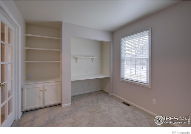 interior space featuring built in desk, carpet, visible vents, and baseboards