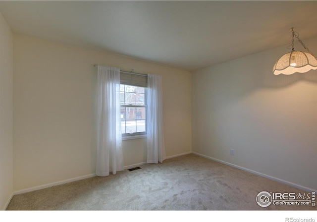 carpeted spare room with baseboards and visible vents