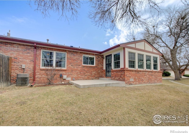 rear view of house with central AC unit, a lawn, fence, a patio area, and brick siding