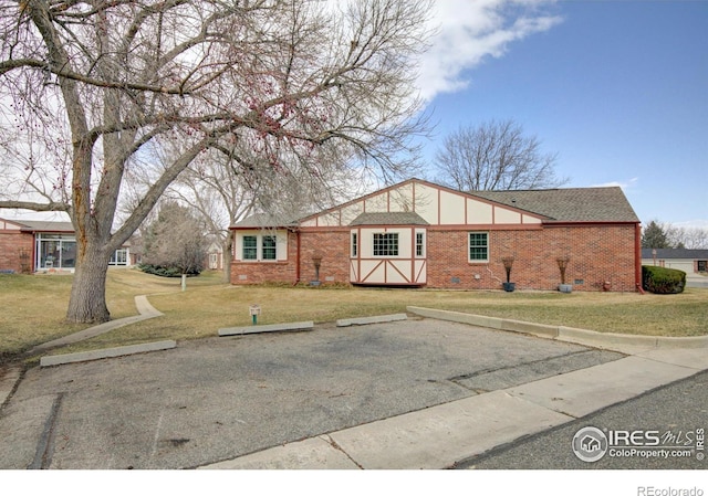 view of front of property featuring uncovered parking, brick siding, crawl space, and a front lawn