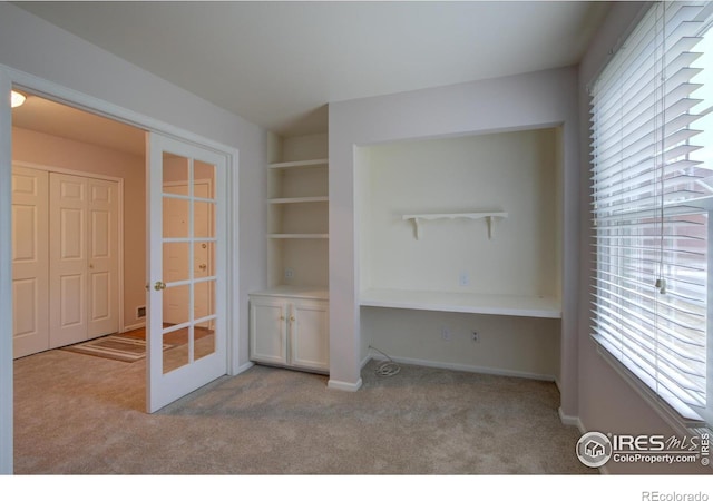 unfurnished office featuring french doors, carpet flooring, and a healthy amount of sunlight
