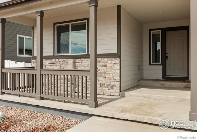 property entrance featuring stone siding and covered porch