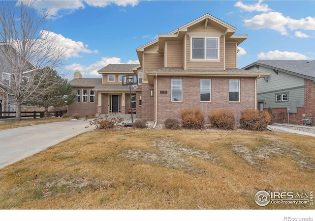 view of front of property with brick siding, driveway, and a front lawn