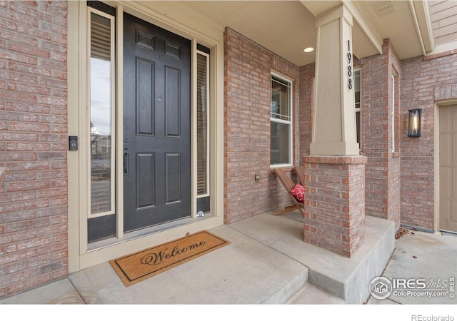 property entrance with a porch and brick siding