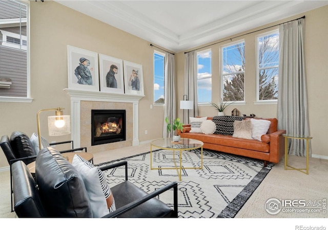 interior space featuring carpet, baseboards, a raised ceiling, and a tile fireplace