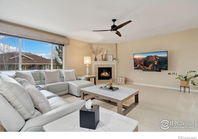 living room featuring carpet floors, a glass covered fireplace, baseboards, and a ceiling fan