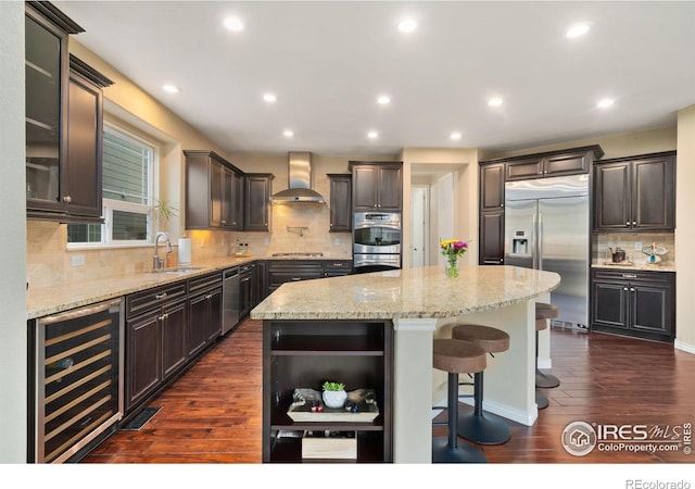 kitchen featuring wine cooler, open shelves, appliances with stainless steel finishes, a sink, and wall chimney exhaust hood