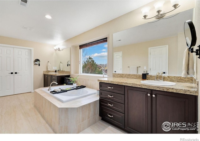 full bathroom with a garden tub, two vanities, a sink, and tile patterned floors