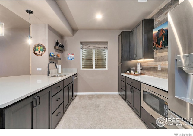 kitchen with light carpet, stainless steel appliances, a sink, hanging light fixtures, and light countertops