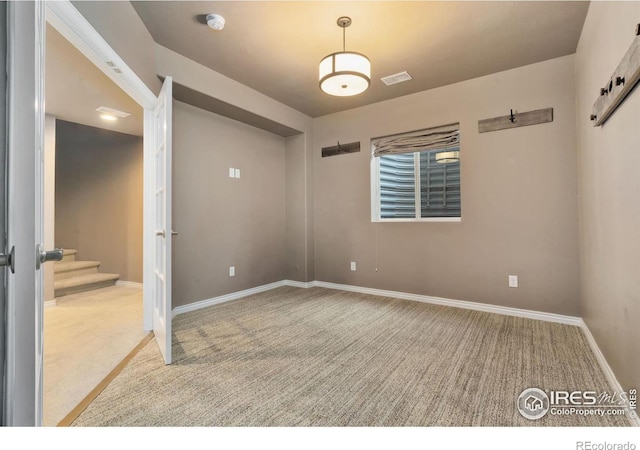 unfurnished room featuring carpet floors, baseboards, stairs, and visible vents