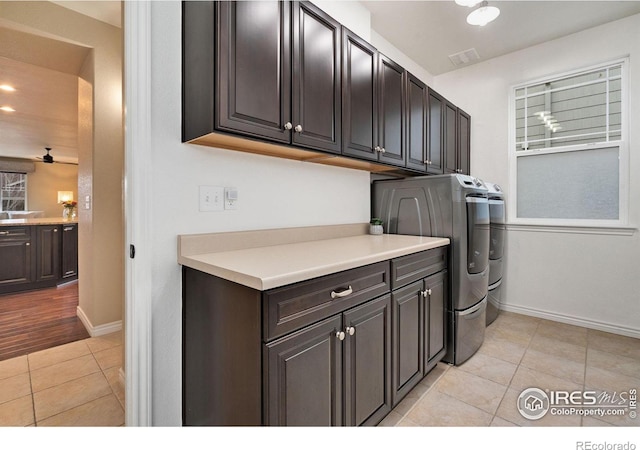 laundry room featuring light tile patterned floors, cabinet space, visible vents, washing machine and dryer, and baseboards