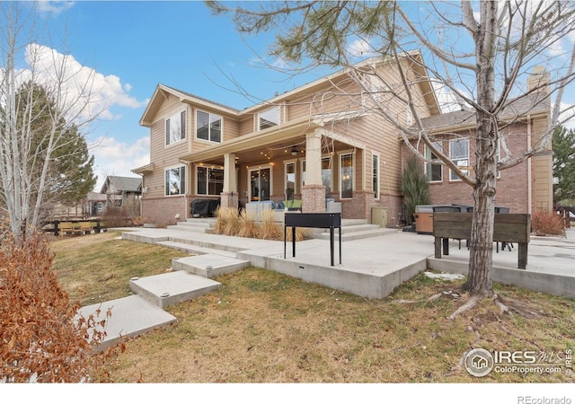 view of front of property featuring a front lawn, a patio, and brick siding