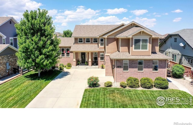 view of front of home with brick siding, a front yard, and roof with shingles