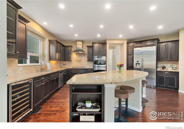 kitchen with a sink, open shelves, beverage cooler, stainless steel appliances, and wall chimney range hood