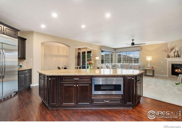 kitchen with open floor plan, dark brown cabinets, a kitchen island, and stainless steel built in refrigerator