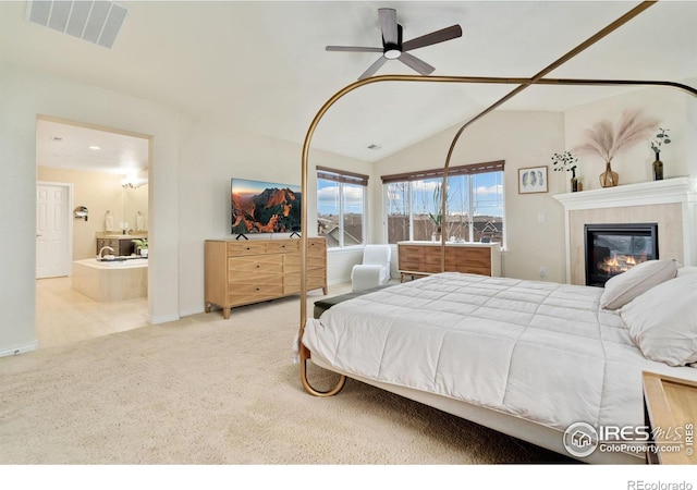 carpeted bedroom featuring a tile fireplace, lofted ceiling, ensuite bathroom, baseboards, and visible vents