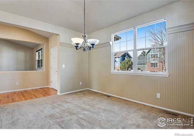 carpeted empty room with visible vents and an inviting chandelier