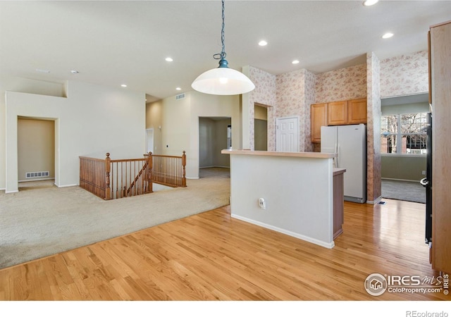 kitchen featuring light colored carpet, visible vents, freestanding refrigerator, light wood finished floors, and wallpapered walls