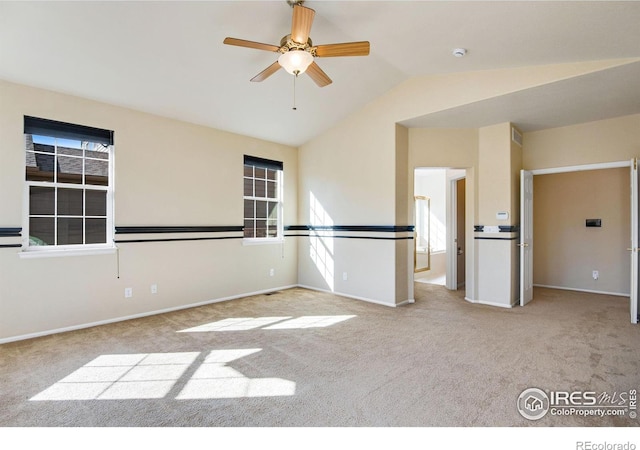 carpeted spare room featuring lofted ceiling, baseboards, and a ceiling fan