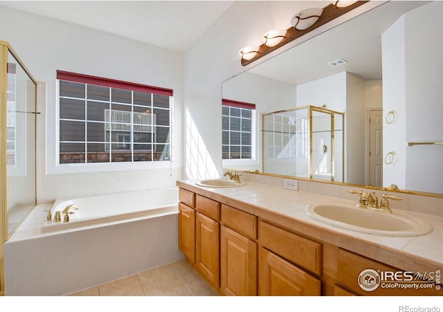 bathroom with a garden tub, a stall shower, a sink, and tile patterned floors