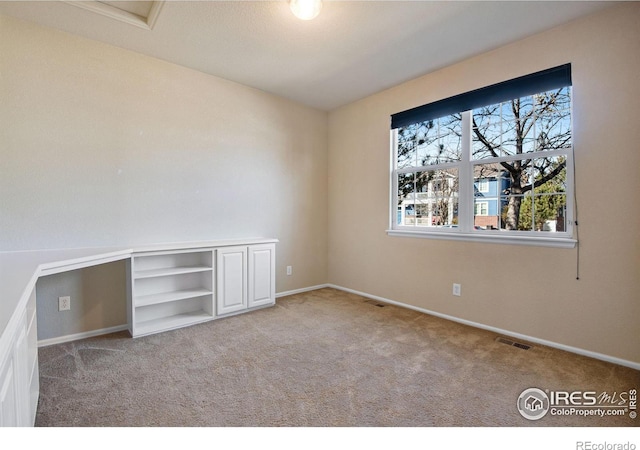 spare room featuring carpet floors, visible vents, and baseboards