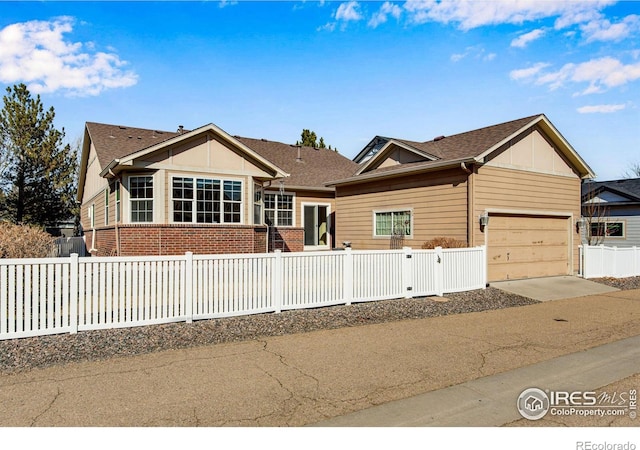 ranch-style house featuring a fenced front yard, concrete driveway, brick siding, and board and batten siding