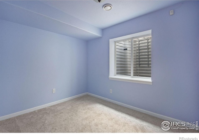 spare room featuring carpet floors and baseboards