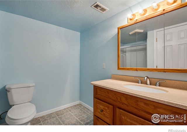 bathroom with visible vents, toilet, vanity, a textured ceiling, and baseboards