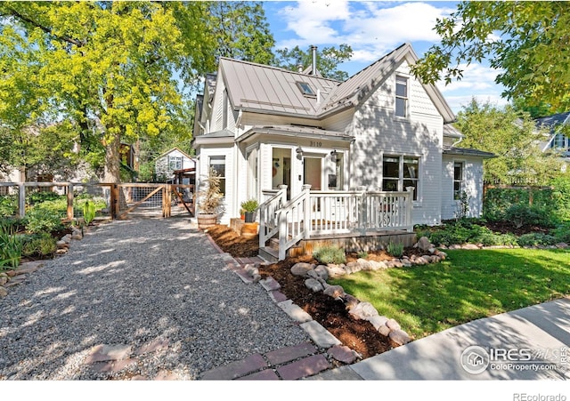 view of front facade featuring metal roof, a standing seam roof, a gate, fence, and a front yard