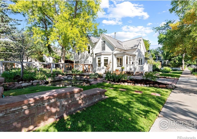 view of front of home featuring metal roof, a front lawn, and a wooden deck