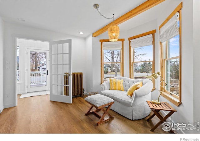 living area with recessed lighting, wood finished floors, baseboards, beam ceiling, and radiator