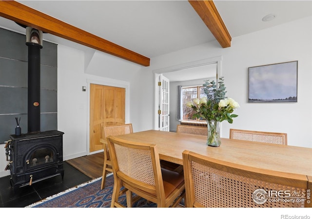 dining space featuring a wood stove and beamed ceiling