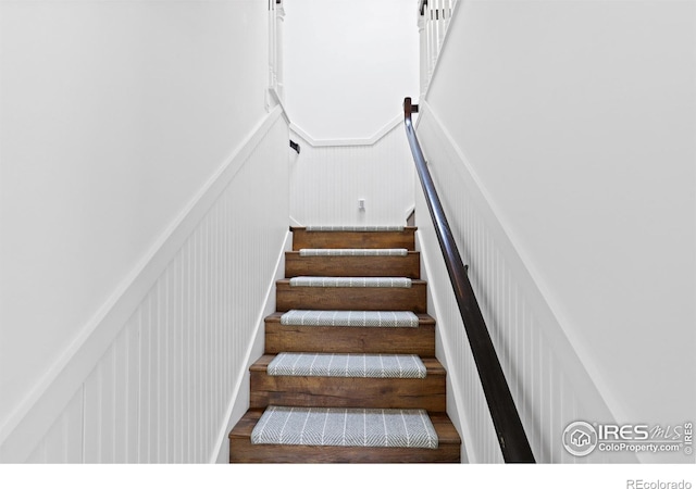 stairs featuring a decorative wall and wood finished floors