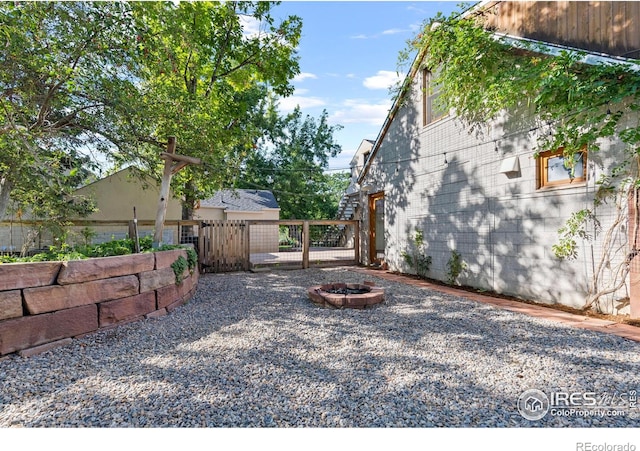 view of yard with a fire pit, fence, and a gate