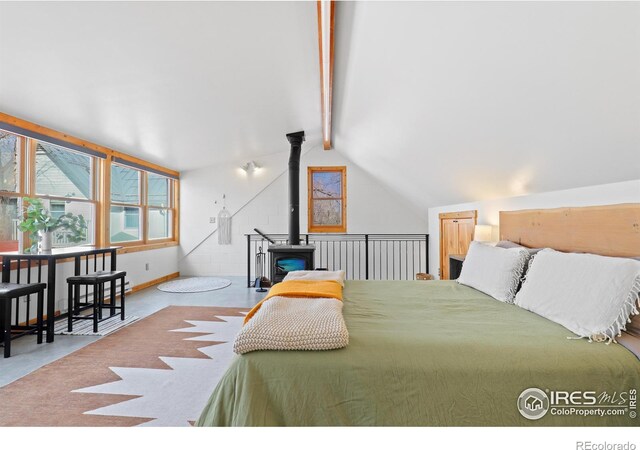 bedroom featuring vaulted ceiling with beams, a wood stove, concrete floors, and baseboards