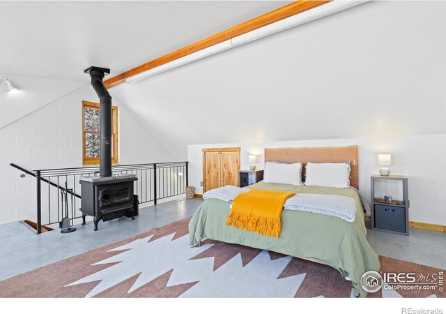 bedroom featuring finished concrete floors, a wood stove, vaulted ceiling with beams, and baseboards